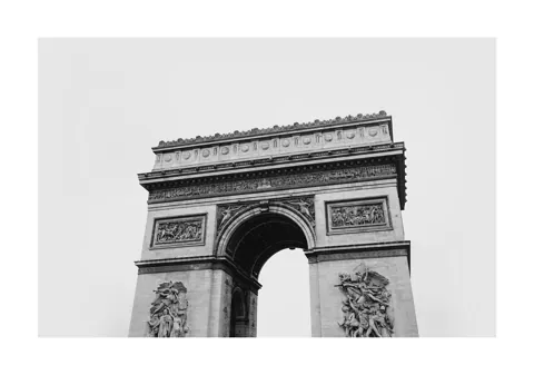 Zwart-witfoto van de Arc de Triomphe in Parijs vanuit kikvorsperspectief