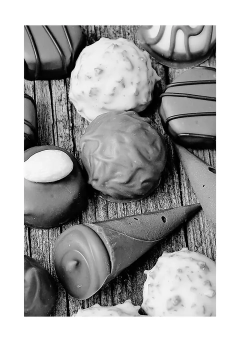 Zwart-wit close-up van ambachtelijke bonbons en truffels op verweerd hout