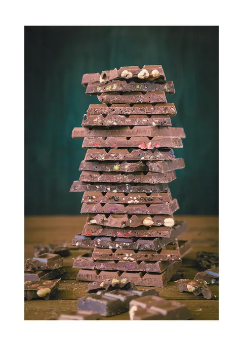 Hoge stapel van verschillende soorten chocoladerepen met noten op een houten tafel