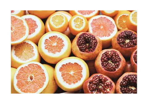 Bovenaanzicht van doorgesneden grapefruits en opengebroken granaatappels vol rode pitjes