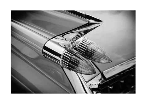 Zwart-wit close-up van puntige achterlichten en een verchroomde vintage autovin