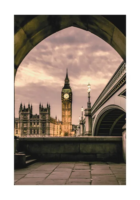 Doorkijkje door een stenen boog op de Big Ben in Londen bij schemering.