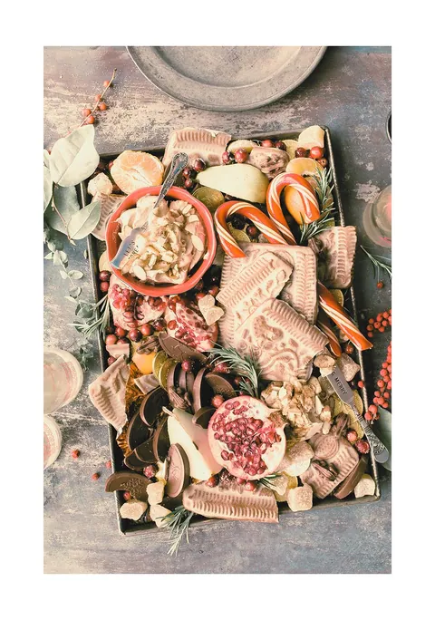 Dienblad vol feestelijke zoetigheden met zuurstokken, koekjes, chocolade en granaatappel