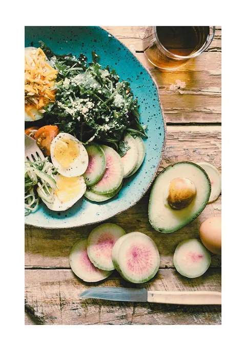 Bovenaanzicht van een saladebowl met avocado, ei en radijs op een houten tafel
