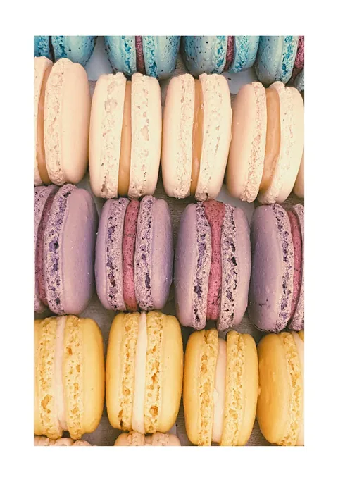 Close-up foto van rijen gekleurde Franse macarons in pastelgeel, paars en wit