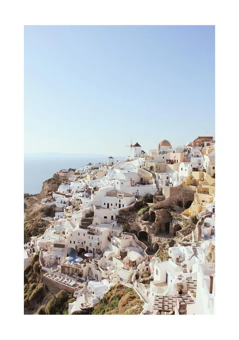 Zonnige foto van witte huisjes en molens op de heuvels van Santorini
