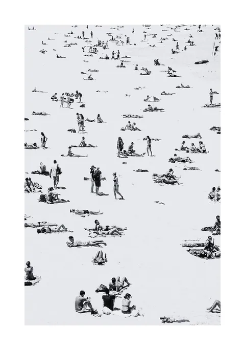 Zwart-wit luchtfoto van strandgangers verspreid over een licht zandstrand.