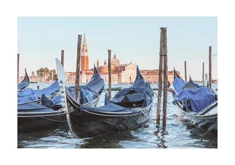 Aangemeerde gondels aan houten palen met op de achtergrond de gebouwen van Venetië